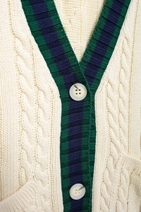 Detailed view of cable-knit pattern with navy and green contrast stripes on V-neck cardigan
