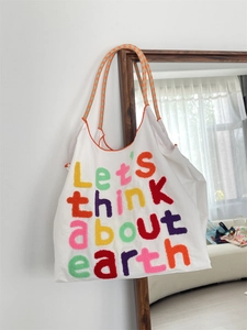 Detail of colorful tufted letter embroidery on a white canvas tote bag for women