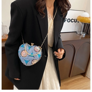 Close-up of heart-shaped evening bag with floral embroidery and sequins on light blue fabric