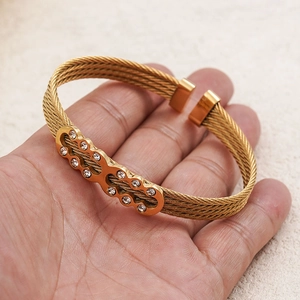 Detailed macro view of woven gold wire rope texture and crystal inlay on the steel bracelet