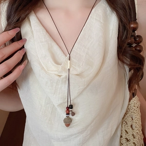 Dettaglio della collana boho con ciondolo a ghianda, corda cerata e perline colorate