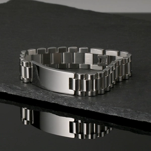 Polished silver stainless steel watch link bracelet on black rock with reflection
