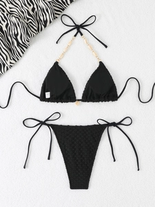 Detail of black waffle-textured bikini set with shell accents and gold metal hardware
