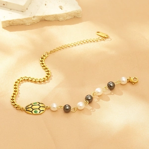 Macro shot of gold-plated snake charm bracelet with pearls and lobster clasp closure