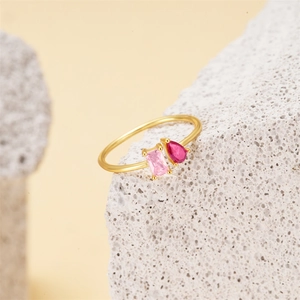 Macro shot of gold ring with pink rectangle and red teardrop gems on stone