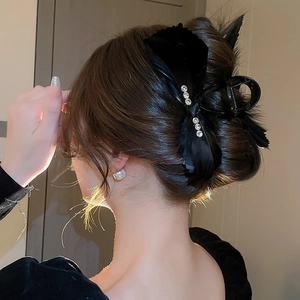 Detail of a black satin bow hair claw clip with rhinestones worn on a brunette updo