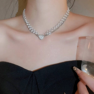 Detailed macro of a multi-layer pearl necklace with a sparkling diamond heart pendant