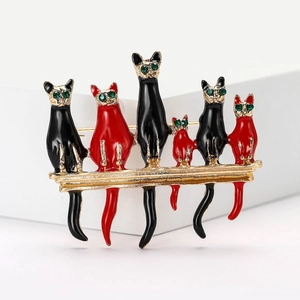 Macro shot of six black and red enamel cats with green rhinestone eyes on a gold brooch