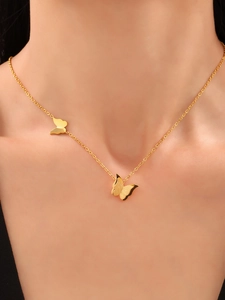 Close-up of a 18K gold butterfly necklace with double matte pendants on a model neck