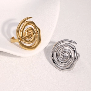 Anelli a spirale aperti minimalisti in oro e argento su sfondo bianco strutturato