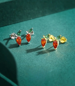 Macro detail of S925 sterling silver carrot earrings with orange and green gemstones
