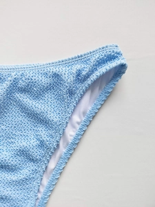 Gros plan sur un bas de bikini bleu clair avec texture gaufrée et bords ondulés