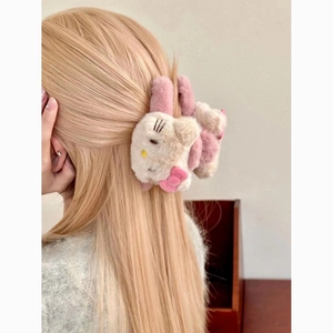 Detail showing the plush Hello Kitty hair claw clip on blonde hair from a side view