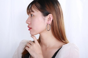Macro shot of large silver hoop earrings with white zircon inlays on a female model