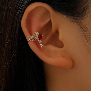 Close-up of a rose gold hummingbird ear cuff with vibrant red and green crystals