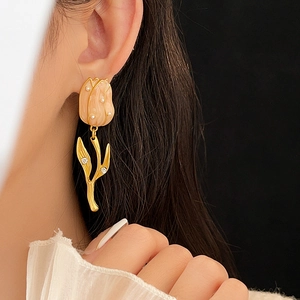 Close-up of elegant tulip earrings with pearls and crystals on a model's ear