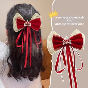 Close-up of red velvet bow hair clip with gold crown and long ribbon streamers