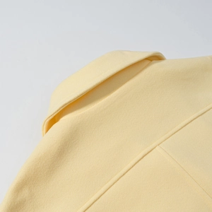 Close-up of lapel collar and stitching details on the light yellow wool blend coat