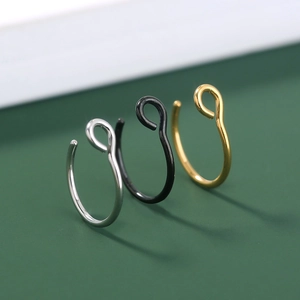 Detailed macro view of minimalist U-shaped nose rings in silver, black, and gold finishes