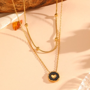 Close-up of 18K gold-plated double-layer necklace with black heart pendant on wood