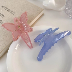 Close-up of pink and blue-purple butterfly hair claws with glossy acrylic texture