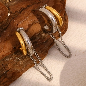 Detail of two-tone 18K gold-plated C-shaped link earrings on a natural stone surface