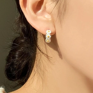 Three-piece daisy silver drop earrings in gold finish on a model side profile