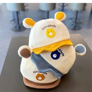 Détail de casquettes souples pour bébé avec écusson ours en jaune, bleu et marron