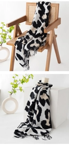Detail showing the black and white cow print scarf texture with elegant fringe edges