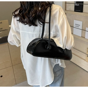 Model view showing the back profile of a large black cylinder shoulder bag with white shirt
