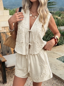 Close-up of beige embroidered vest and shorts set featuring intricate texture and tie detail