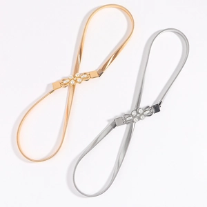 Detail of elastic metal spring belts in gold and silver with pearl bow buckle