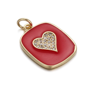 Detail shot of a golden rectangular pendant with red enamel heart and shimmering zircons