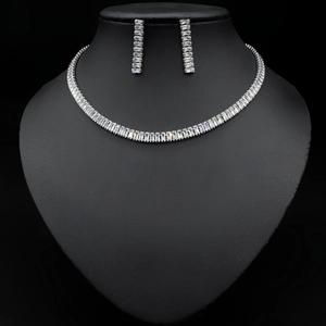 Close-up of silver necklace and earring set with rectangular clear zircon on black stand