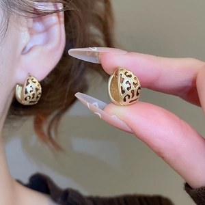 Détail des boucles d'oreilles dorées en forme de C avec motif léopard ajouré rétro
