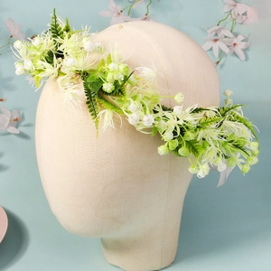 Detail of bohemian bridal flower crown with white blossoms and green fern on mannequin