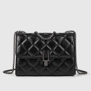 Detail of black quilted leather shoulder bag with dark metal chain and buckle clasp