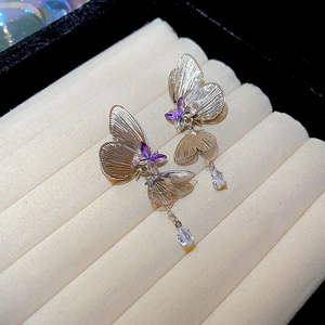 Macro view of silver butterfly tassel earrings with purple gems and teardrop zircon