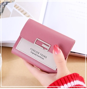 Close-up of pink three-fold leather wallet with metal buckle and contrast stitching details