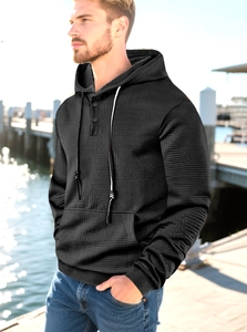 Detail of black hoodie with textured quilted fabric and buttoned neckline in outdoor setting
