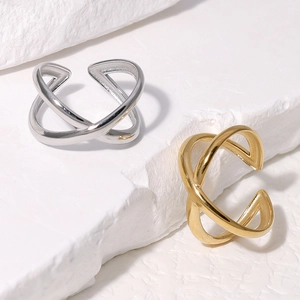 Macro detail of minimalist gold and silver cross open rings on white stone surface