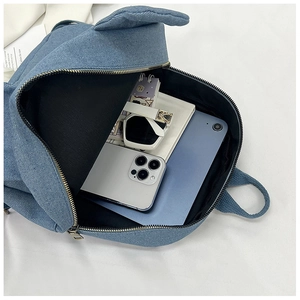 Internal capacity of blue denim backpack showing tablet, phone, and sunglasses storage