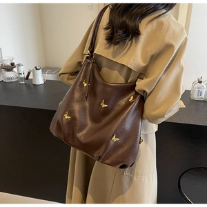 Detail of a large brown faux leather hobo bag with golden 3D butterfly ornaments