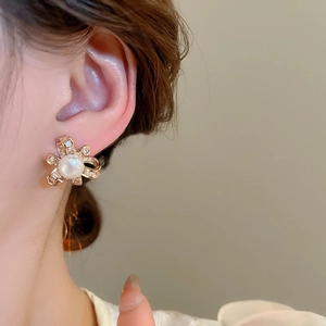 Detailed view of elegant gold bow stud earrings with white pearl and sparkling zircons