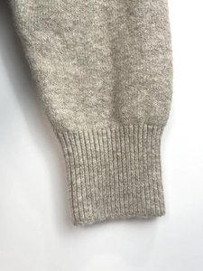 Macro detail of the light grey knitted sleeve featuring soft elastic ribbed cuff texture