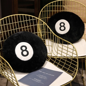 Detailed view of plush black 8-ball pillow texture on a modern gold metal chair