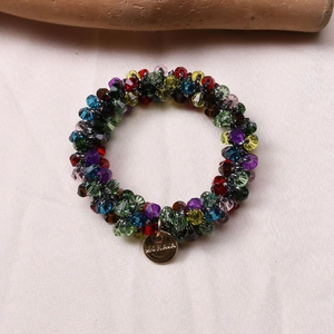 Detail of colorful faceted crystal beads bracelet with engraved gold metal charm