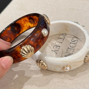 Close-up of resin bracelets with tortoiseshell pattern, shell charms and pearls