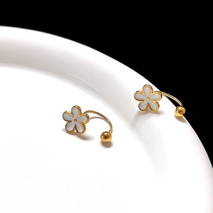 Macro shot of gold floral earrings with white enamel petals on a porcelain plate