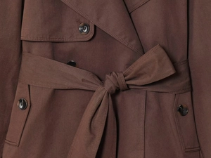 Detail of dark brown trench coat with amber buttons and cotton twill belt